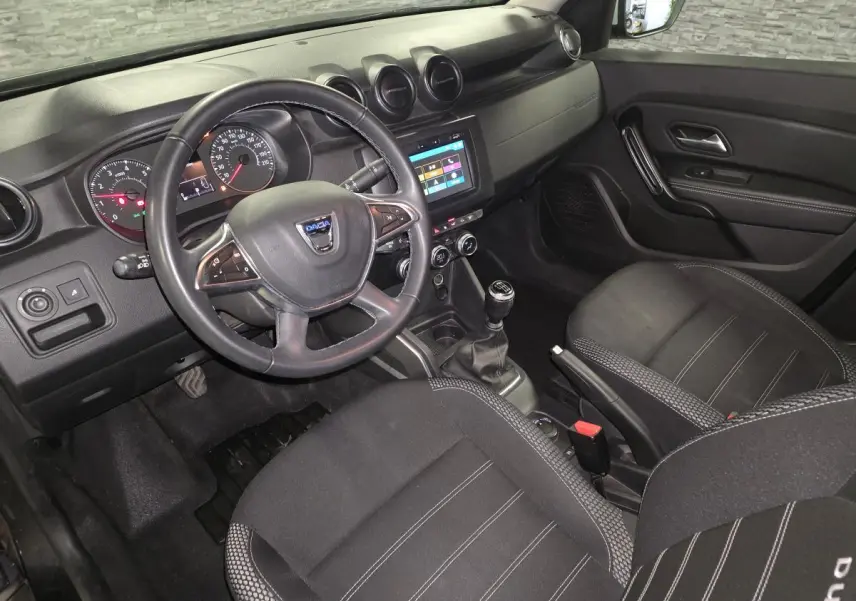 Vue intérieure côté conducteur du Dacia Duster 2019 avec tableau de bord noir et volant multifonction.
