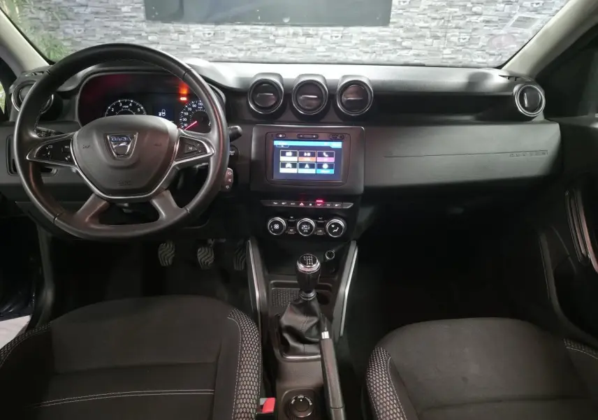 Vue intérieure avant du Dacia Duster 2019 noir, avec volant multifonction, écran tactile et boîte manuelle.