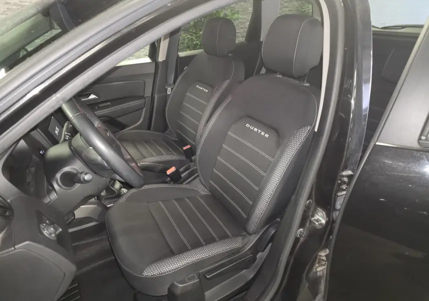 Vue intérieure côté conducteur du Dacia Duster noir 2019, sièges tissu avec logo Duster brodé.
