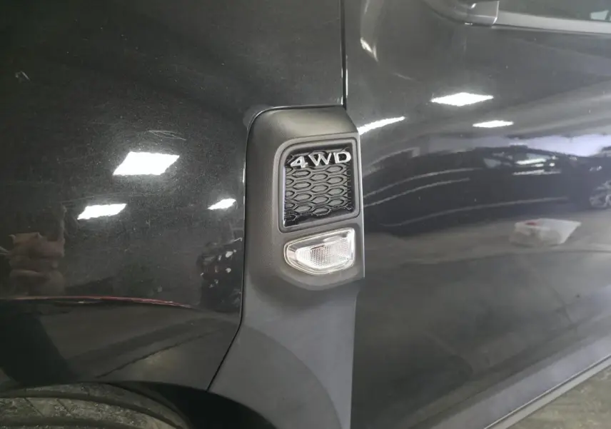 Gros plan sur l'aile avant gauche noire nacrée du Dacia Duster 1.3 TCe 4x4 avec badge 4WD et répétiteur latéral.