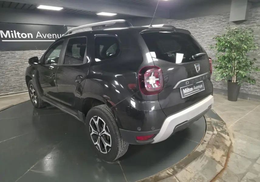 Vue 3/4 arrière droite du Dacia Duster noir nacré 2019 avec jantes alliage et bouclier arrière gris clair.