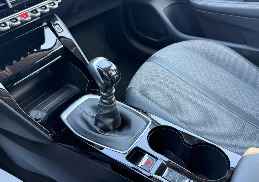 Gros plan sur la console centrale et levier de vitesses manuelle de la Peugeot 208 1.2 100ch Allure avec siège tissu gris.