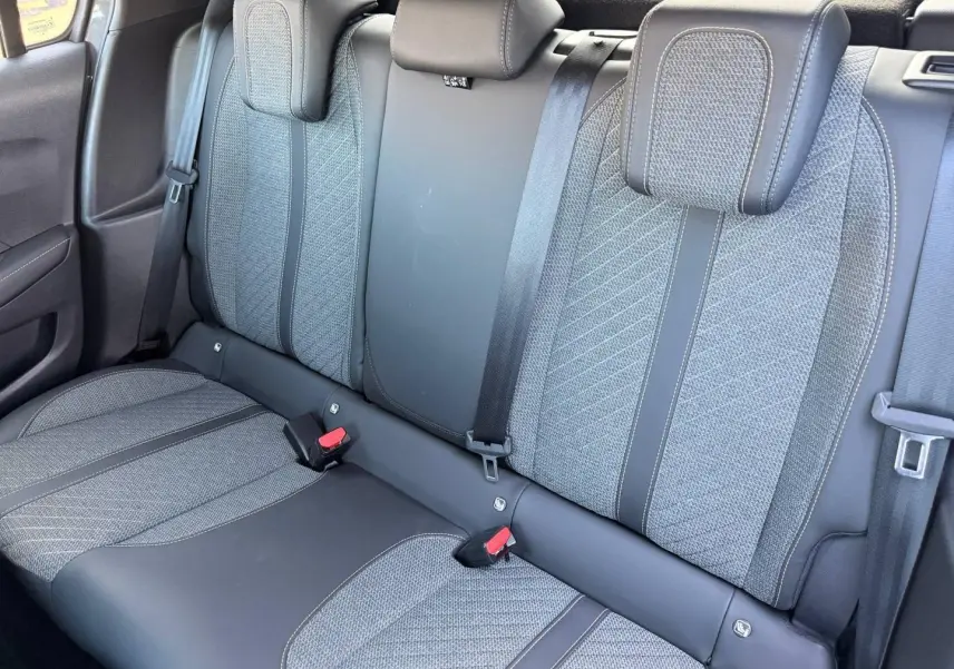Vue rapprochée de la banquette arrière grise tissu et cuir de la Peugeot 208 1.2 100ch Allure 2025, avec ceintures et appuie-têtes.