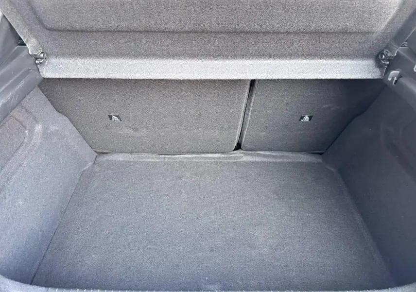Coffre ouvert de la Peugeot 208 1.2 100ch gris Selenium, montrant l'espace de chargement et la banquette arrière rabattable.