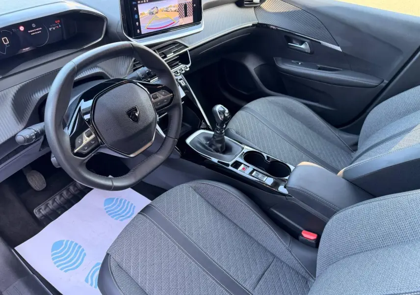 Intérieur avant droit de la Peugeot 208 gris Selenium avec volant compact, écran tactile et boîte manuelle.
