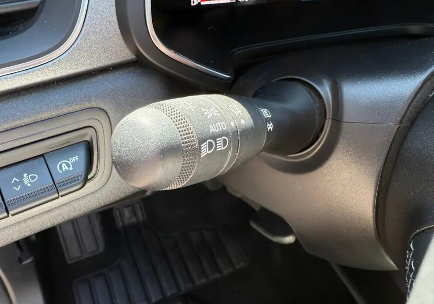Gros plan sur la commande des phares et essuie-glaces du Renault Captur 2025, intérieur noir avec détails gris.