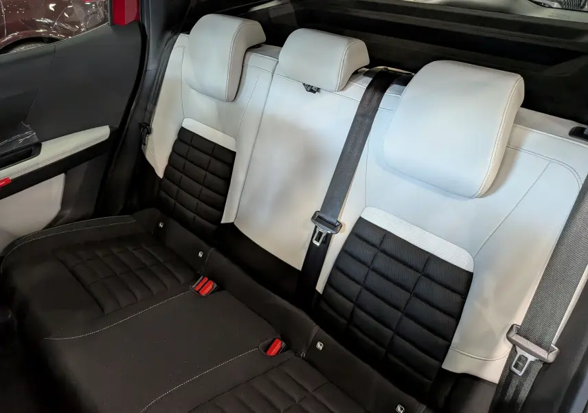 Vue intérieure arrière des sièges bicolores noir et blanc du Citroën C3 Aircross hybride 2026 avec ceintures de sécurité visibles.
