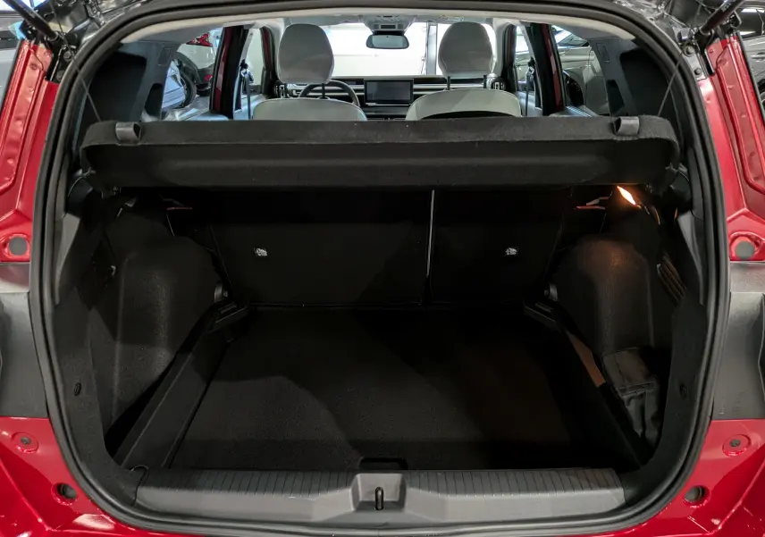 Coffre ouvert vue arrière d'une Citroën C3 Aircross rouge Elixir avec intérieur clair et tablette de coffre noire.