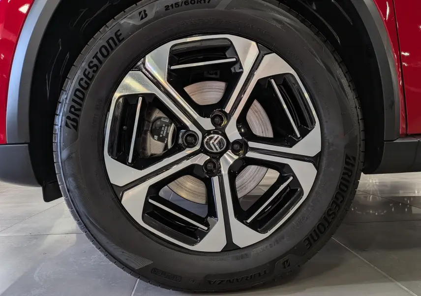 Gros plan sur la roue avant droite du Citroën C3 Aircross rouge Elixir avec jante alliage bicolore et logo Citroën central.