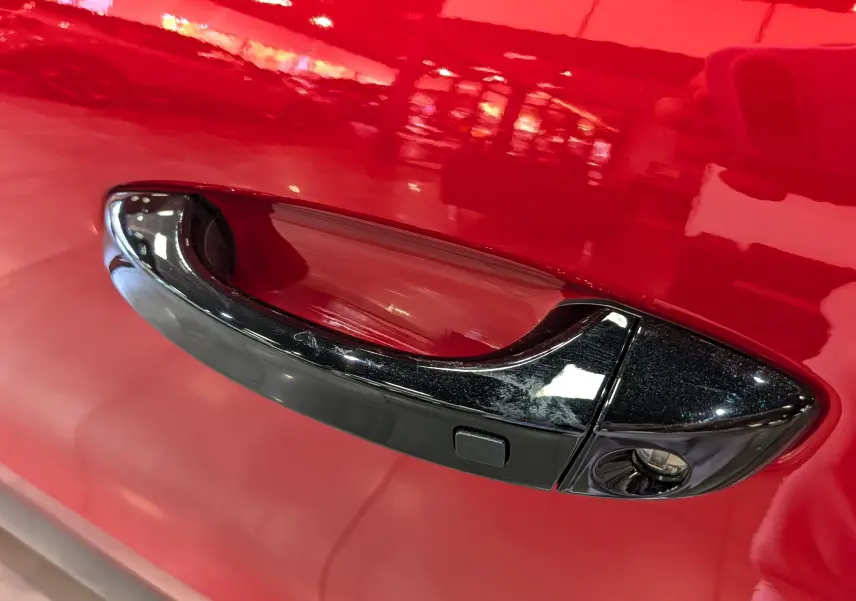 Poignée de porte noire en gros plan sur la porte rouge Elixir d'une Citroën C3 Aircross hybride 2026.
