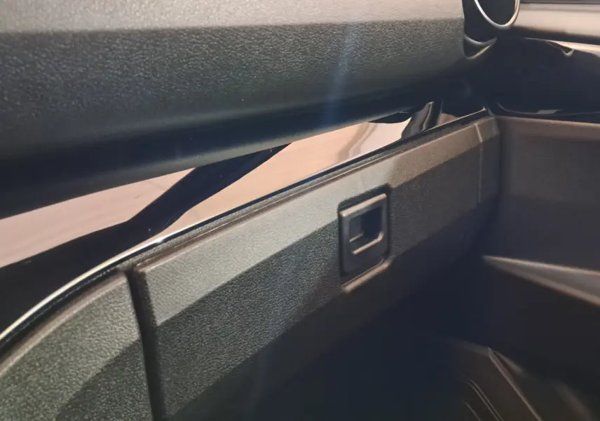 Gros plan sur la boîte à gants noire à ouverture carrée de l'intérieur d'une Aixam Ambition rouge 2025.