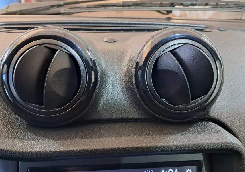 Gros plan sur les deux aérateurs ronds noirs du tableau de bord de l'AIXAM AMBITION rouge 2025.