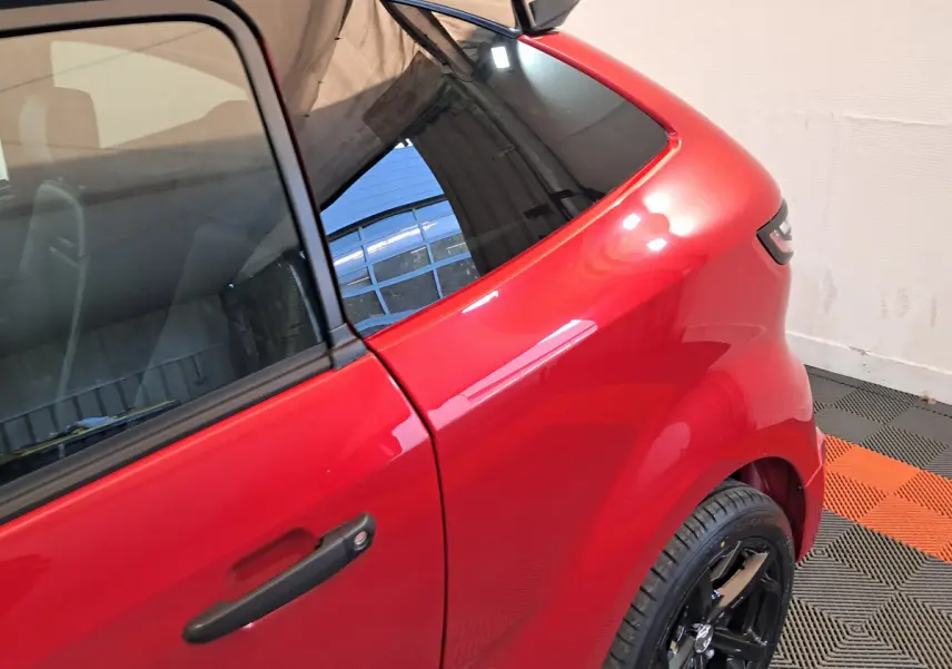 Vue rapprochée du côté gauche arrière d'une AIXAM AMBITION rouge 2025 avec jante noire brillante.