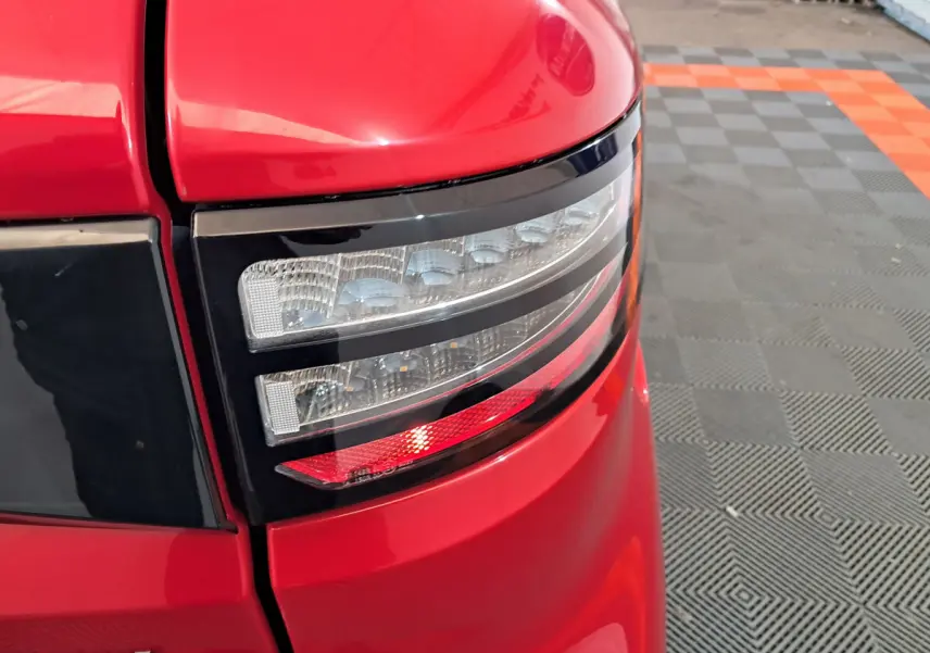 Gros plan sur le feu arrière droit rouge de l'AIXAM AMBITION 0.5 City Coupe Sport 2025 avec finition brillante.