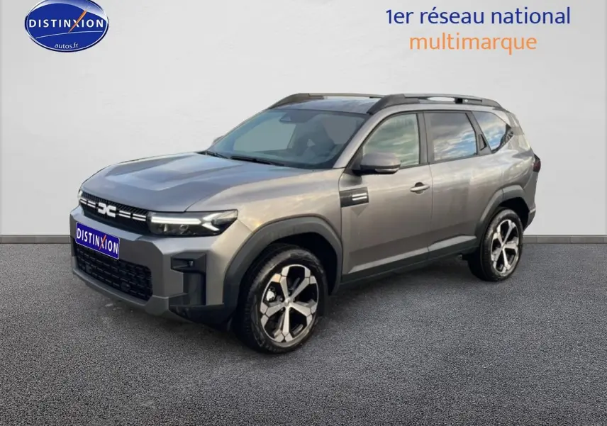SUV Dacia Bigster gris schiste en 3/4 avant droit, avec jantes alliage diamantées et barres de toit noires.
