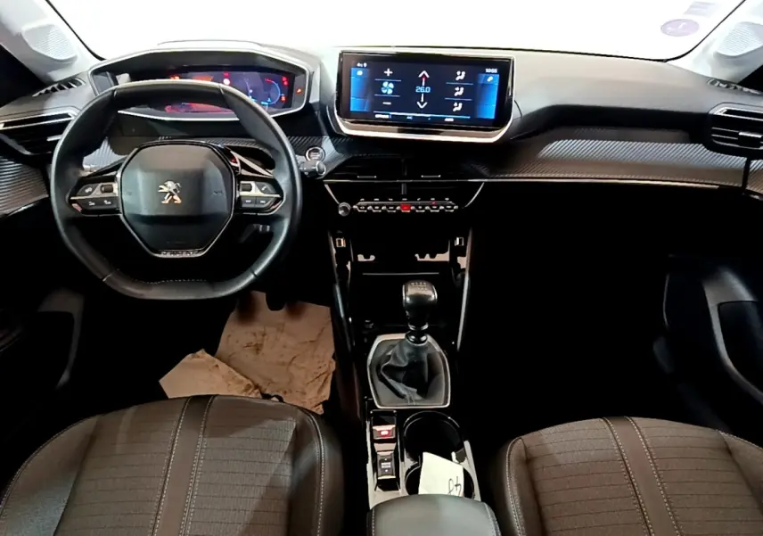 Vue intérieure avant de la Peugeot 208 PureTech 100 S&S Allure Business 2021, tableau de bord noir avec écran tactile central.