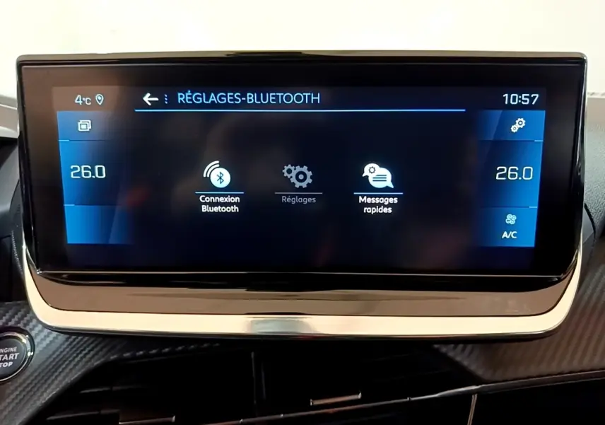 Écran tactile central de la Peugeot 208 blanc, affichant les réglages Bluetooth et la température à 26°C.