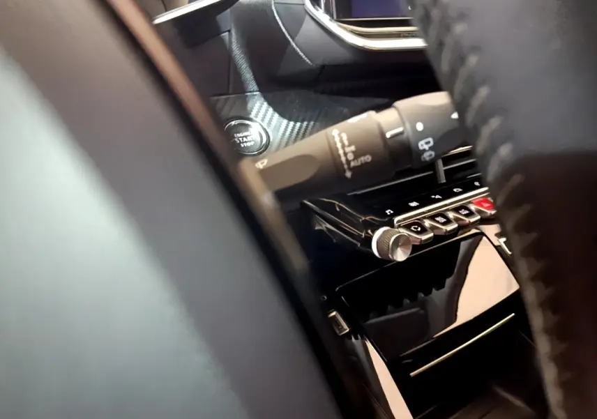 Détail intérieur du tableau de bord de la Peugeot 208 blanc, avec bouton démarrage et commandes sur la console centrale.