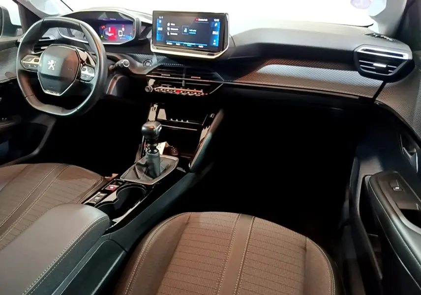 Intérieur de la Peugeot 208 PureTech 100 S&S Allure Business 2021, vue de profil droit sur tableau de bord et console centrale noire.