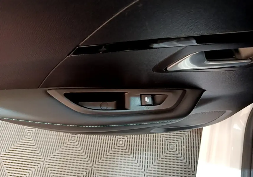 Poignée intérieure noire avec bouton de verrouillage sur la porte côté conducteur d'une Peugeot 208 blanche 2021.