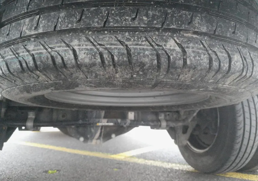 Gros plan sous le Renault Master blanc montrant la roue de secours et les roues jumelées arrière sur sol asphalté.