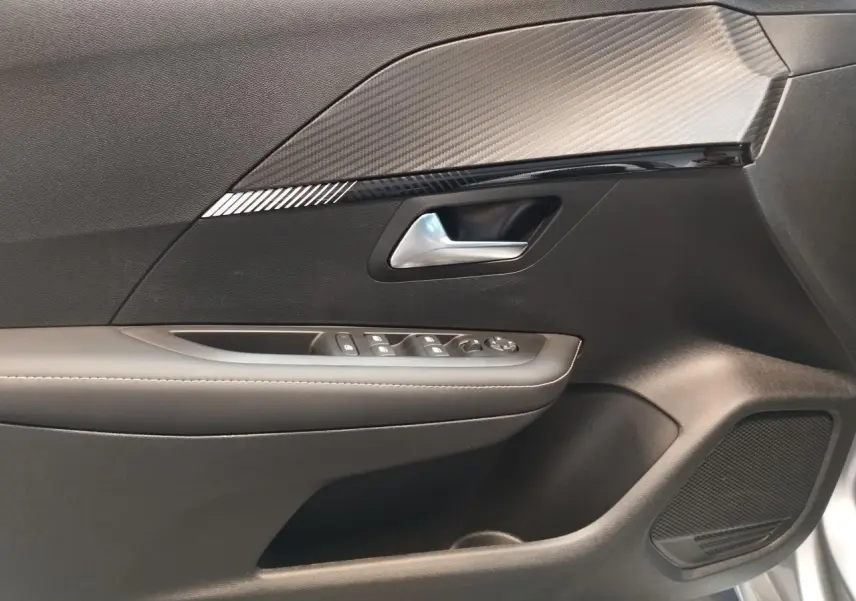 Gros plan sur la porte côté conducteur du Peugeot 208 gris Artense 2024, avec commandes de vitres et insert décoratif noir.