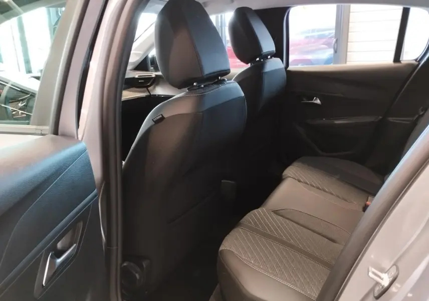 Vue intérieure arrière côté droit du Peugeot 208 2024 gris Artense, montrant les sièges arrière en tissu et cuir.