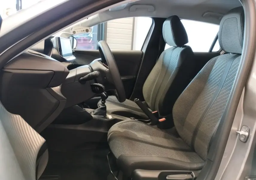 Intérieur de la Peugeot 208 2024 gris Artense, vue côté conducteur montrant les sièges et la boîte manuelle.