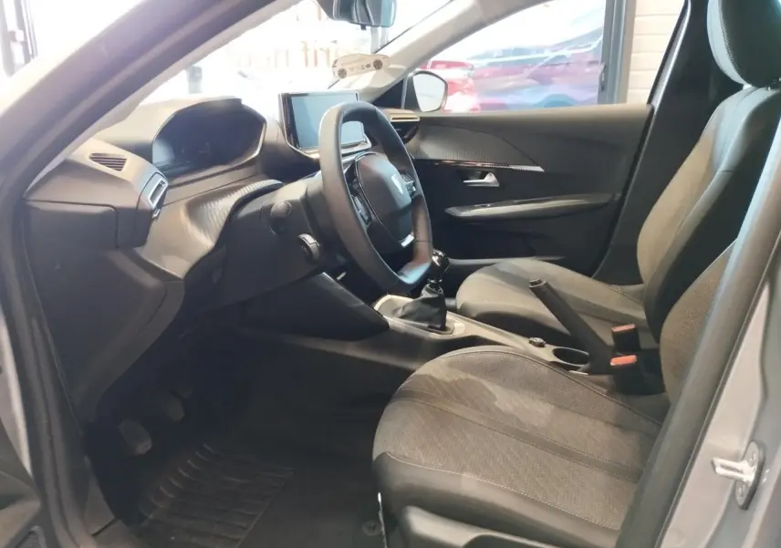 Intérieur côté conducteur de la Peugeot 208 2024 gris Artense, avec volant compact et boîte manuelle visible.
