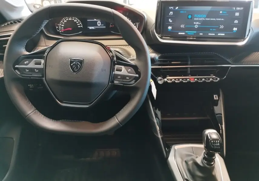 Vue intérieure centrée sur le volant Peugeot et la console centrale avec boîte manuelle dans une Peugeot 208 2024 gris Artense.