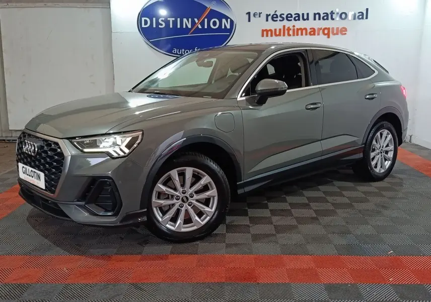 Audi Q3 Sportback gris foncé en 3/4 avant droit, avec calandre hexagonale et jantes alliage visibles.