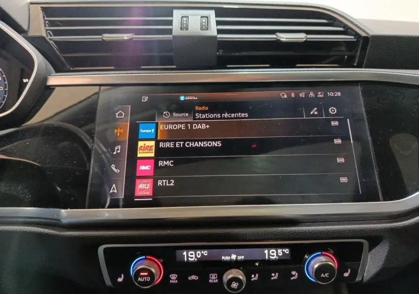 Écran tactile central et commandes climatisation bicolores dans l’habitacle d’un Audi Q3 Sportback gris foncé, vue frontale rapprochée.