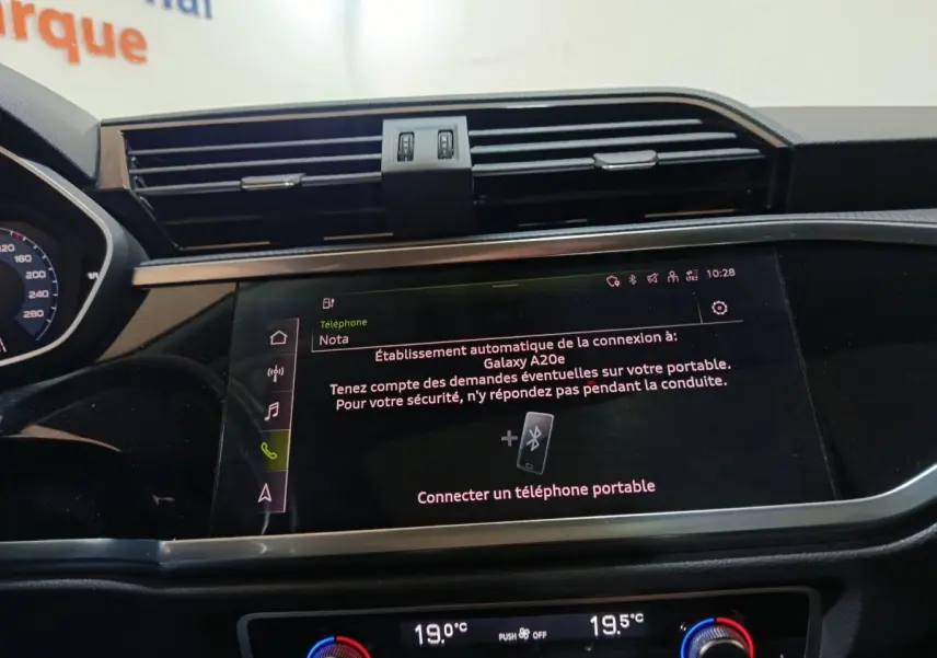 Vue rapprochée de l’écran tactile central et de la console de climatisation du tableau de bord de l’Audi Q3 Sportback gris foncé.