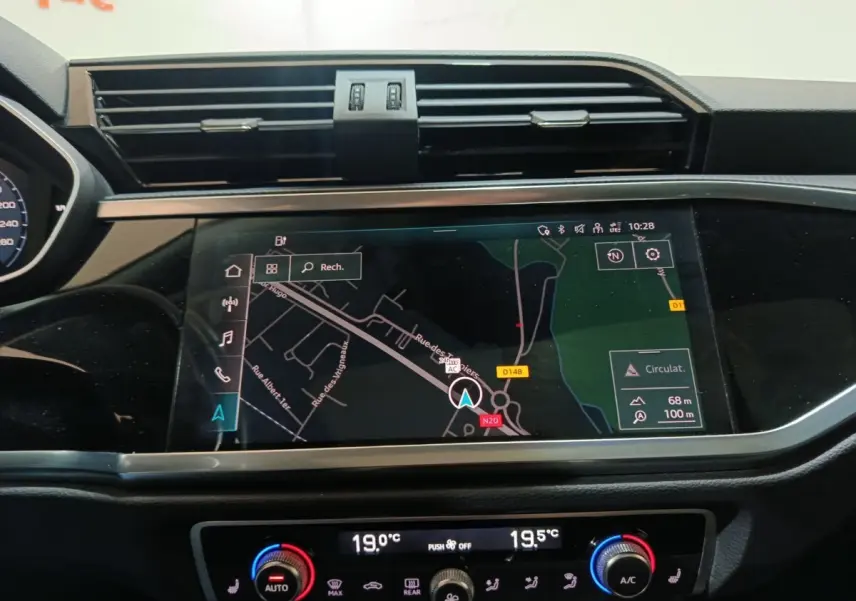 Vue rapprochée du tableau de bord de l'Audi Q3 Sportback gris foncé avec écran tactile de navigation et commandes climatisation digitales.
