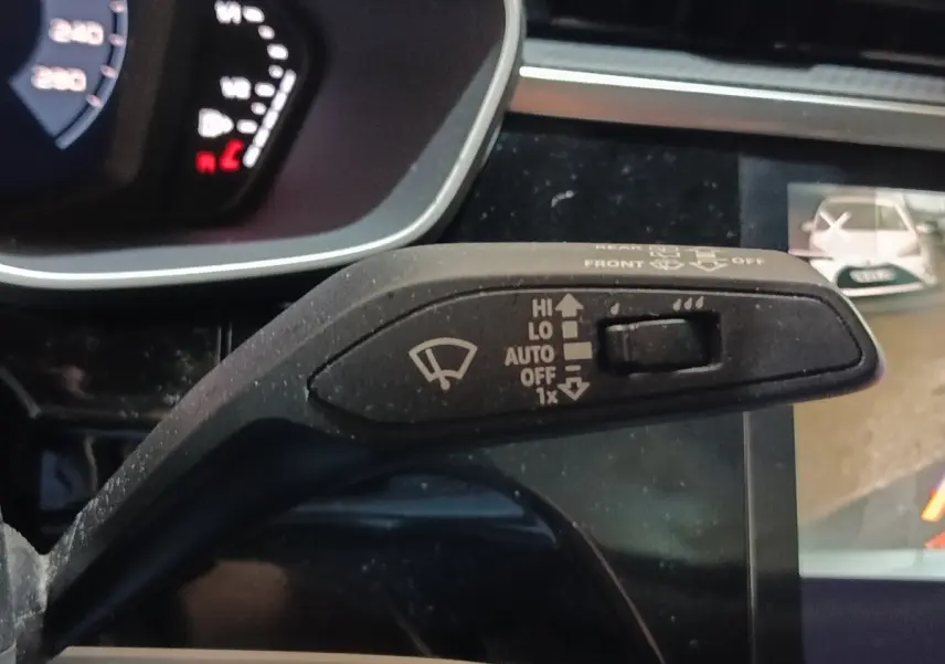 Gros plan sur la commande d’essuie-glace à gauche du volant dans l’Audi Q3 Sportback gris foncé, tableau de bord partiellement visible.