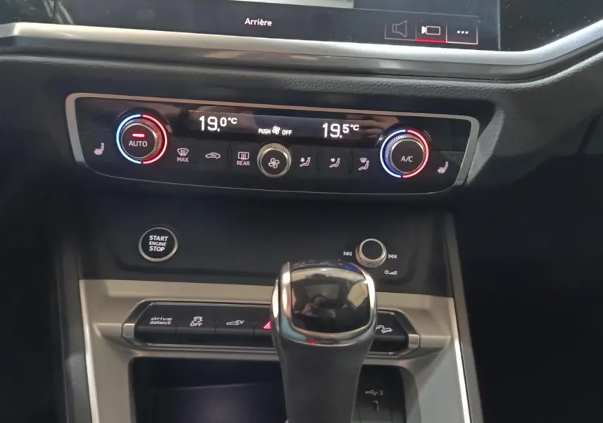 Gros plan sur la console centrale de l'Audi Q3 Sportback 45 TFSI e, montrant la commande de climatisation digitale et le levier de vitesse.