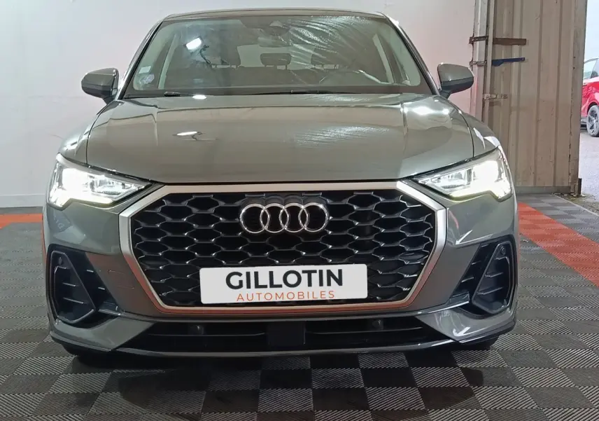 Vue avant d’un Audi Q3 Sportback gris foncé avec calandre hexagonale et phares LED allumés en intérieur.