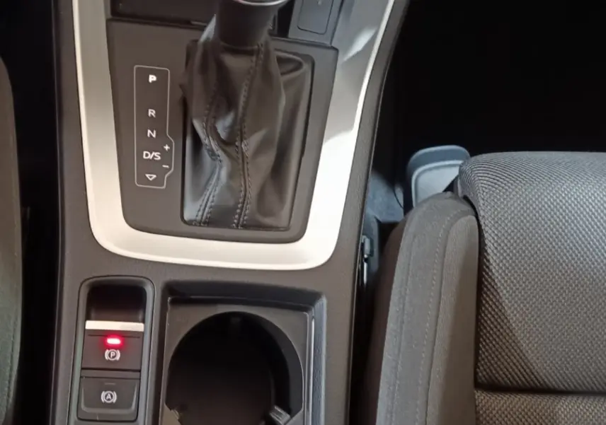 Vue rapprochée de la console centrale de l’Audi Q3 Sportback 45 TFSI e, avec levier de vitesse et porte-gobelets noirs.
