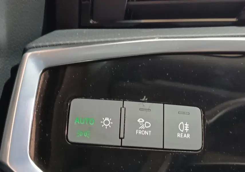 Gros plan sur les commandes d’éclairage du tableau de bord de l’Audi Q3 Sportback gris foncé, avec boutons auto, phares avant et arrière.