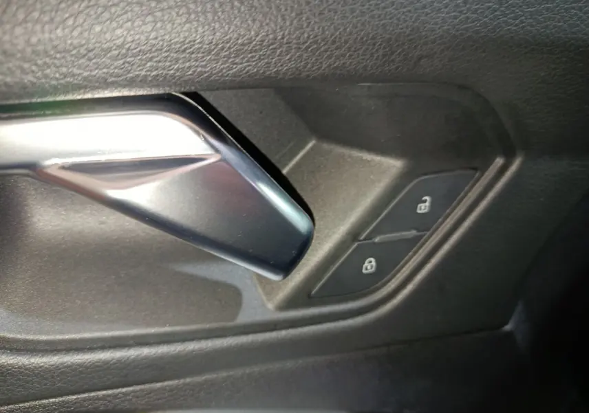 Gros plan sur la poignée intérieure argentée et les boutons de verrouillage sur la portière noire de l'Audi Q3 Sportback.