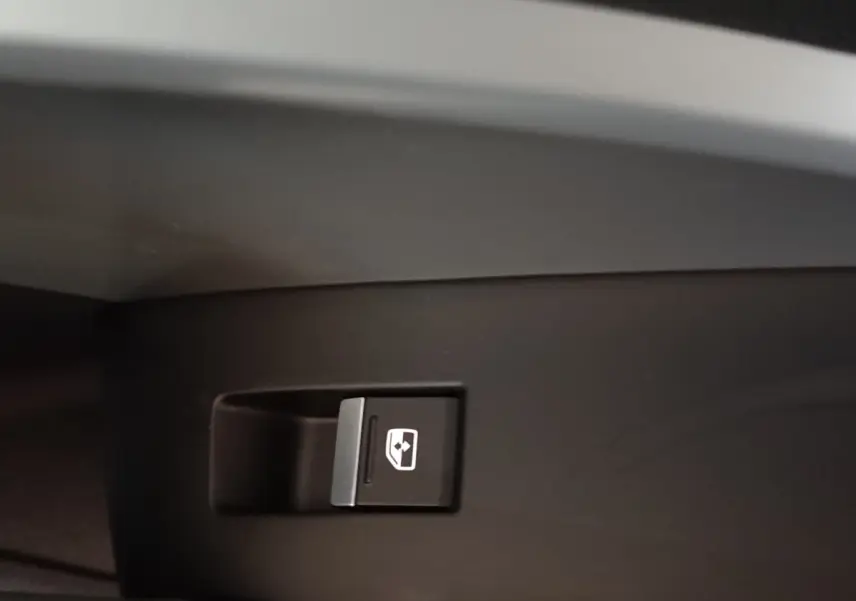 Gros plan sur le bouton de commande de la vitre électrique côté droit de l’Audi Q3 Sportback gris foncé.