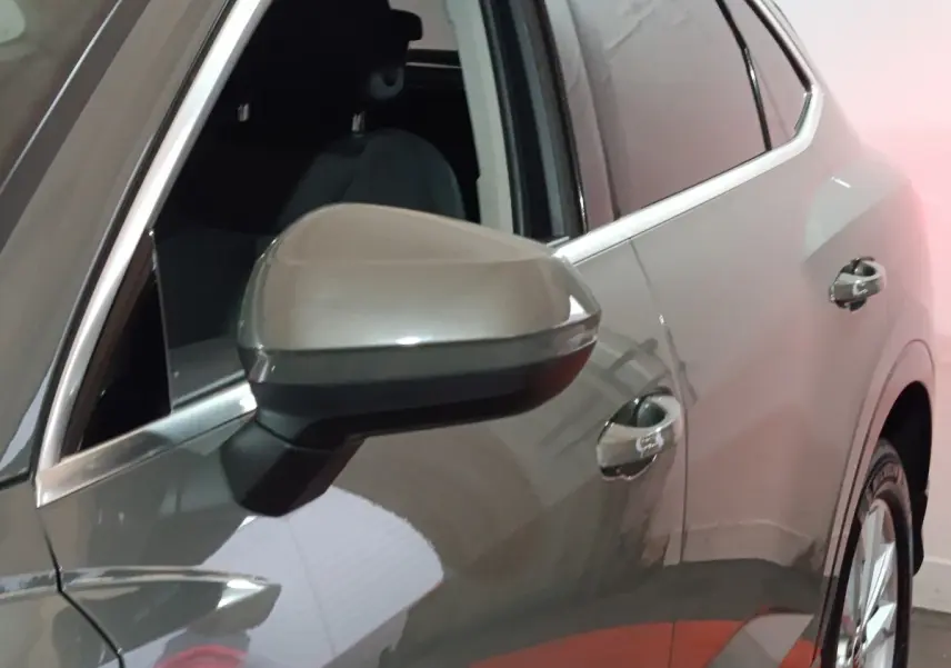 Gros plan sur le rétroviseur et la portière côté gauche d’un Audi Q3 Sportback gris foncé en intérieur.