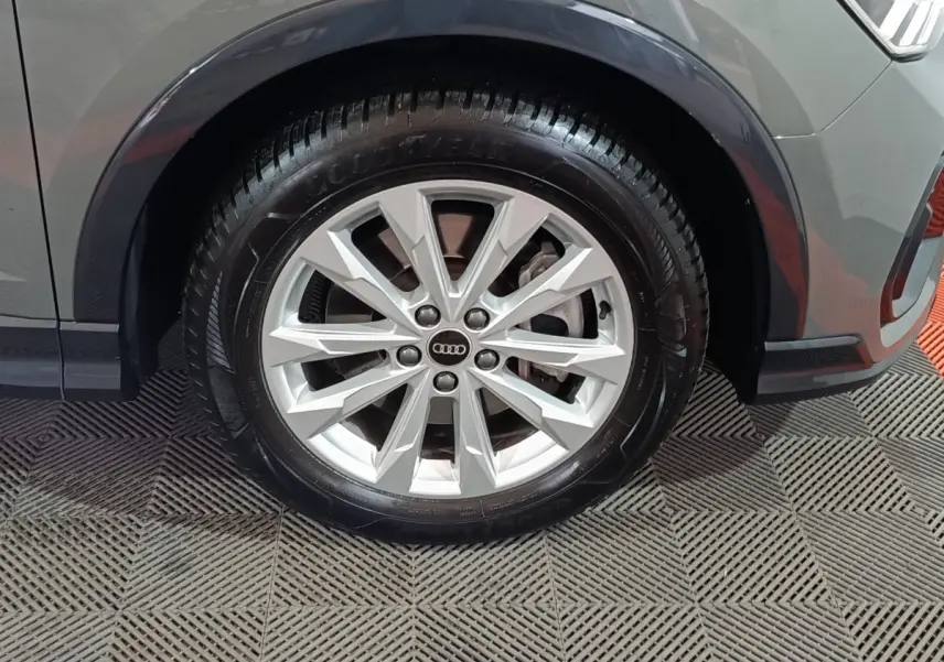 Gros plan sur la roue avant droite gris foncé de l’Audi Q3 Sportback avec jante argentée à multiples branches.