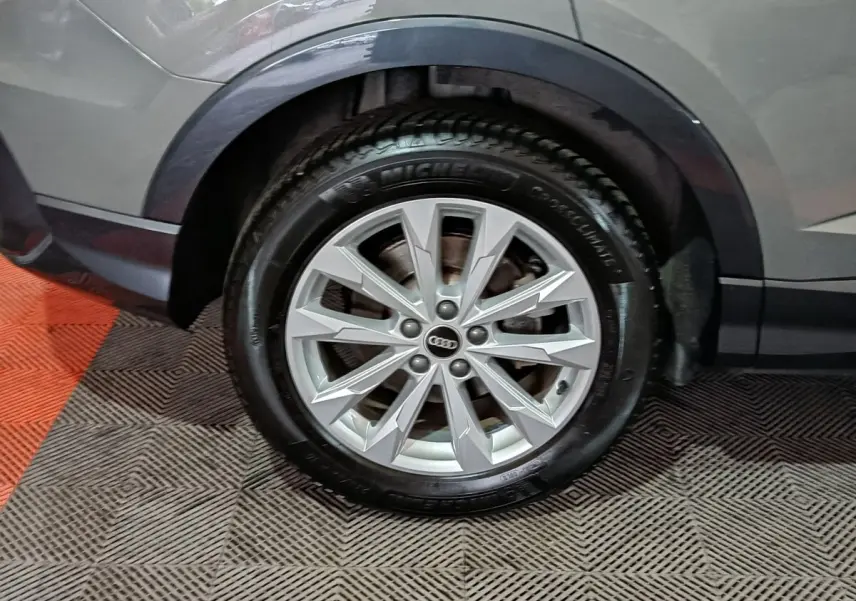 Gros plan sur la roue avant droite gris foncé d’un Audi Q3 Sportback avec jante alu à multiples branches.