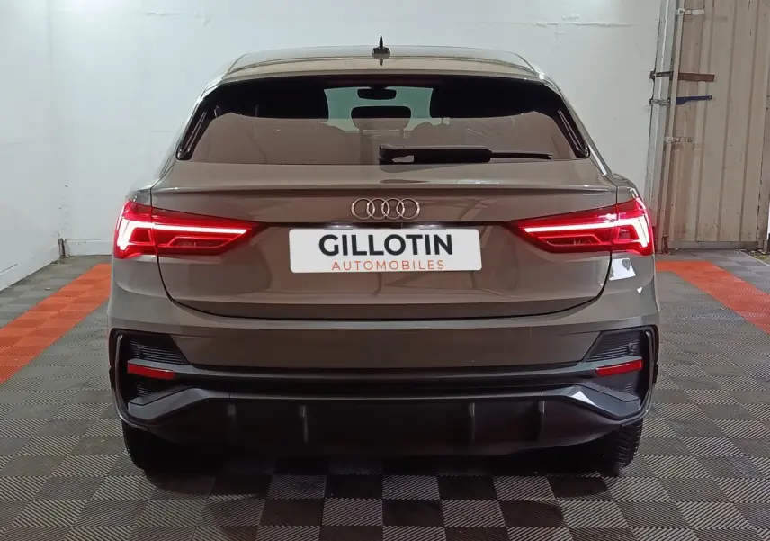 Vue arrière d'un Audi Q3 Sportback gris foncé avec feux LED allumés dans un garage.