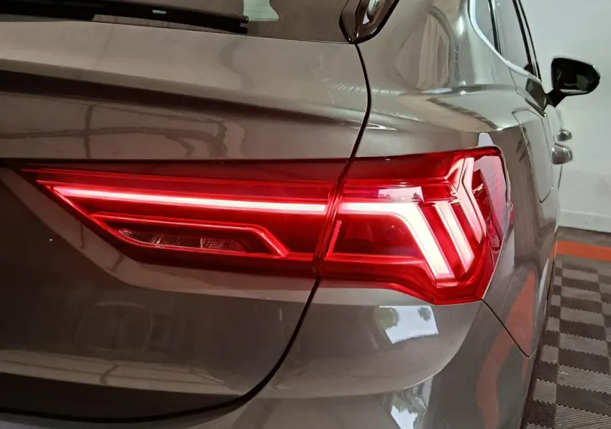 Gros plan sur le feu arrière droit allumé d’un Audi Q3 Sportback gris foncé, vue depuis l’arrière côté droit.