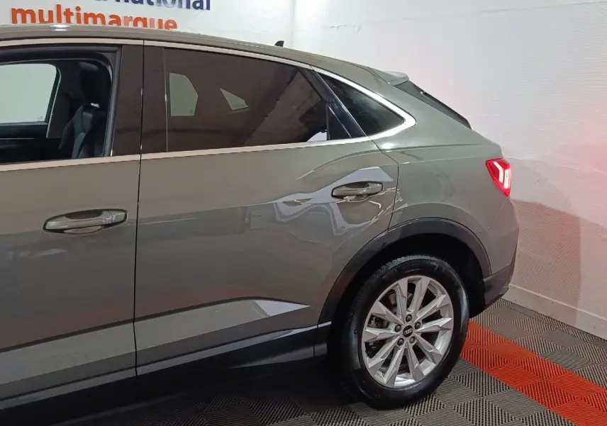 Vue latérale droite sur l’arrière d’un Audi Q3 Sportback gris foncé avec jante alliage et vitres teintées.