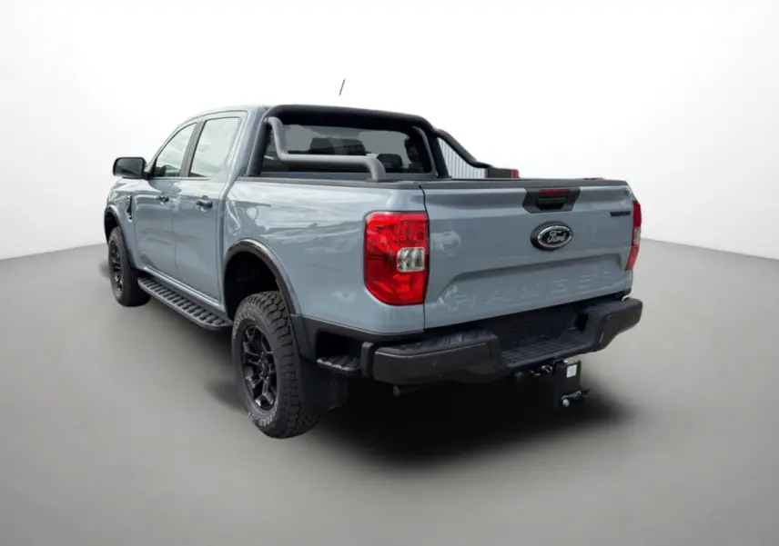 Ford Ranger gris commandeur en 3/4 arrière droit avec arceaux noirs et attelage visible sur fond neutre.