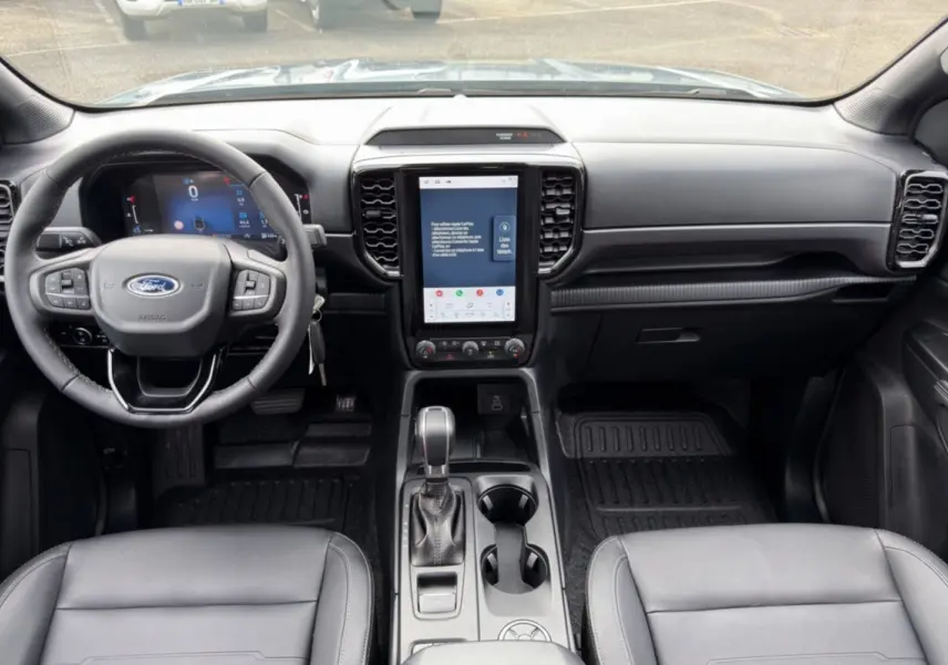Vue intérieure avant du Ford Ranger 2026 gris, avec tableau de bord numérique et écran tactile vertical central.
