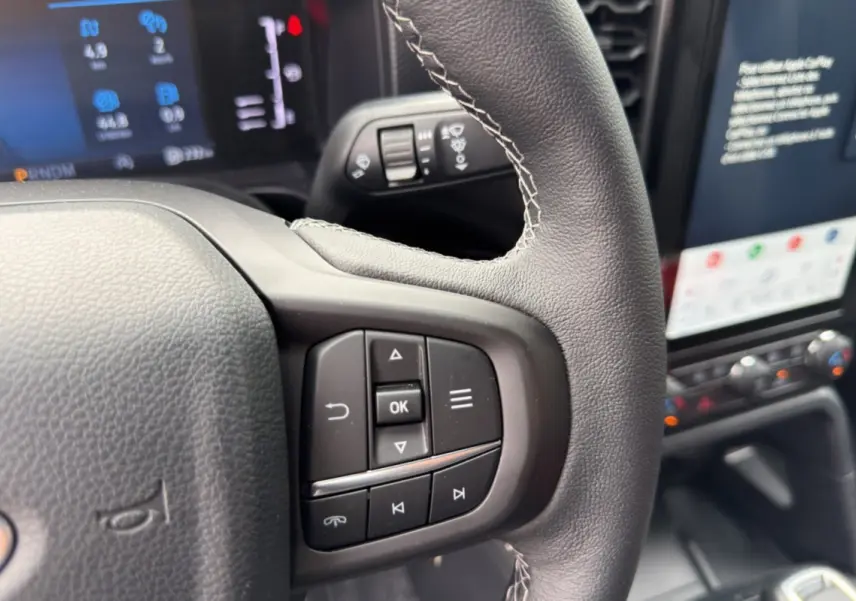 Gros plan sur le volant cuir multifonctions du Ford Ranger gris commandeur, avec écran tactile et commandes au volant visibles.